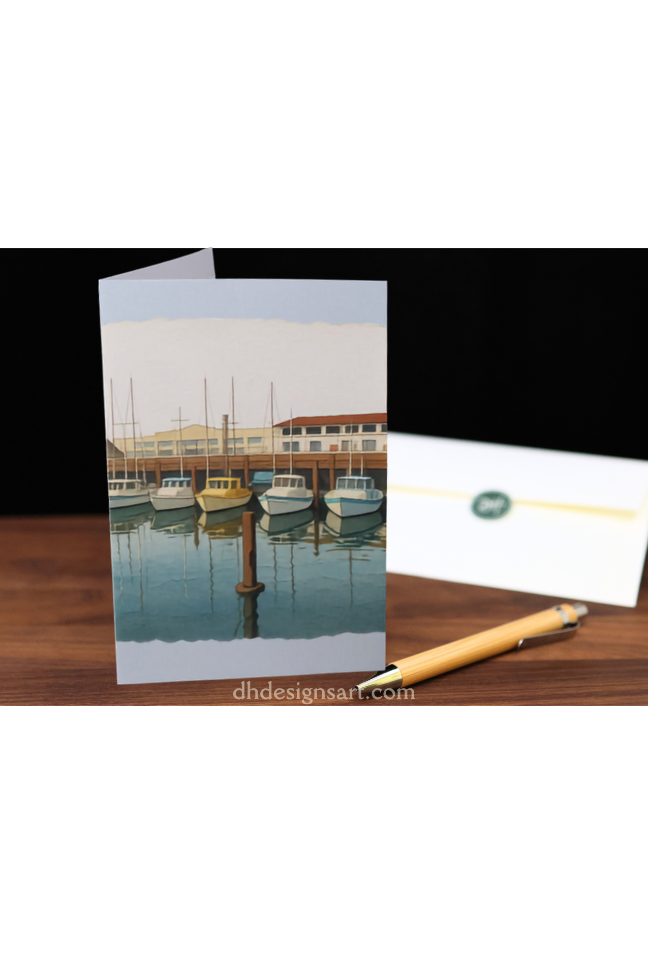 Greeting card with marina scene and pen on wooden surface