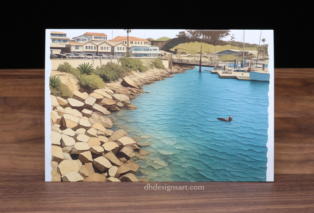 Blank notecard with a scenic view of a coastal area with a floating otter in the water, houses, boats, and a rocky shoreline, set upon a wooden desk. dhdesignsart.com