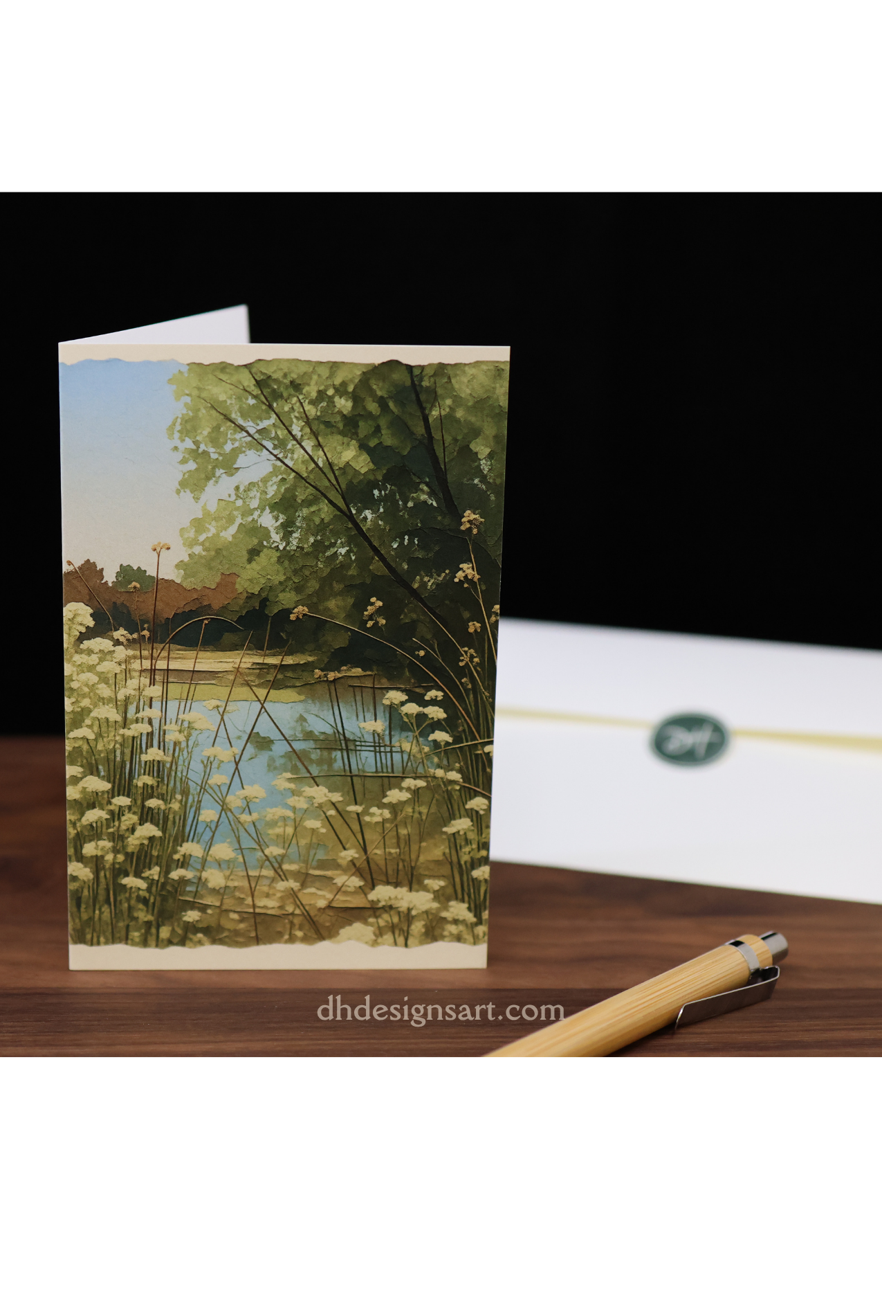 Blank notecard depicting a pond at the San Luis Reserve, on a wooden desk with a pen and envelope - dhdesignsart.com.