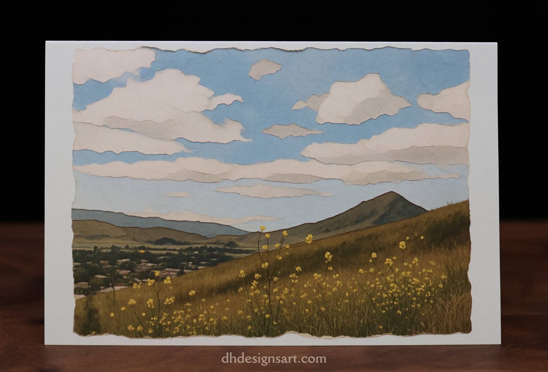 Blank notecard with a landscape illustration with fields, hills, and a blue sky and white clouds. dhdesignsart.com.