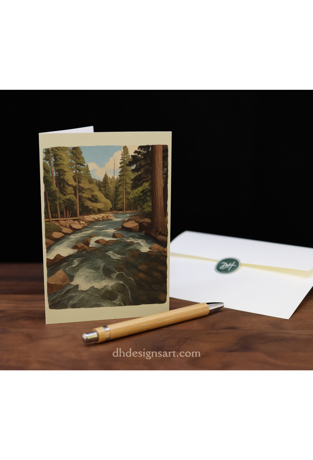 Blank notecard with a Yosemite pine forest and creek, an envelope on a wooden desk, and 'dhdesignsart.com' branding.
